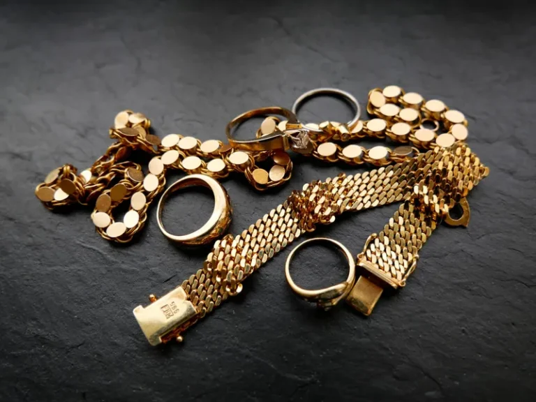 Goldschmuck mit Ringen und Armbändern auf dunkler Fläche