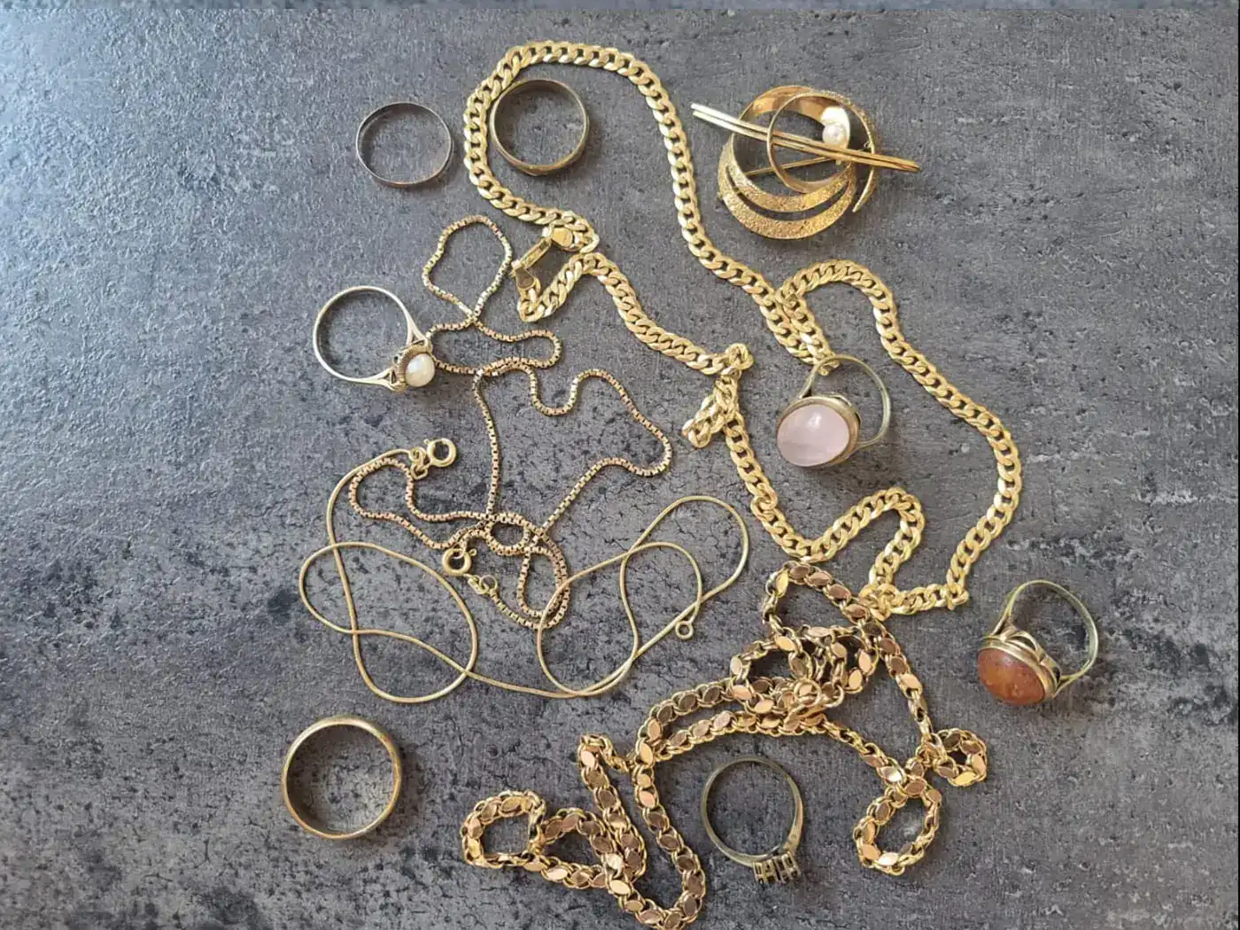 Goldketten, Ringe und eine Brosche auf Schiefer