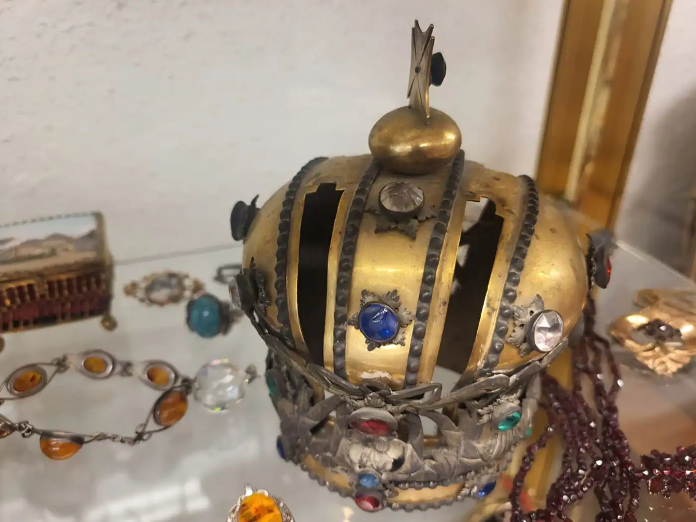 Vergoldete Krone mit farbigen Steinen, daneben Schmuck